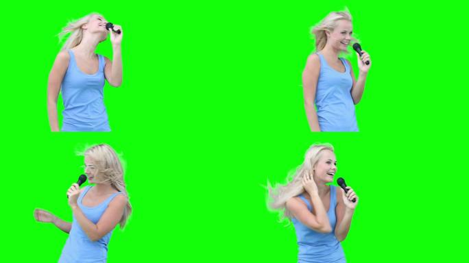 一个金发女人在绿色背景下对着麦克风唱歌