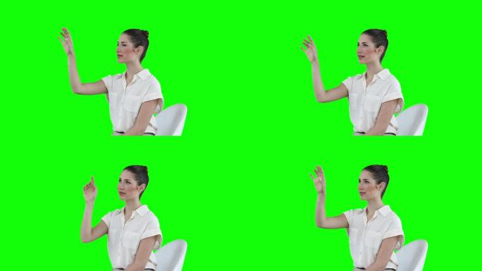 坐着的女人在绿色背景下的虚拟触摸屏上滚动图标