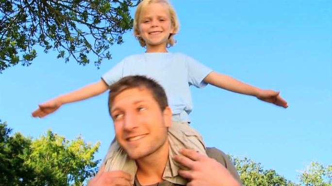 父亲在公园里把快乐的儿子扛在肩上