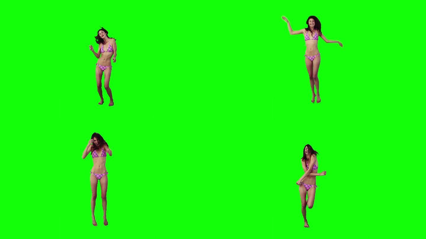 一个穿着比基尼的女人在绿色背景前跳舞