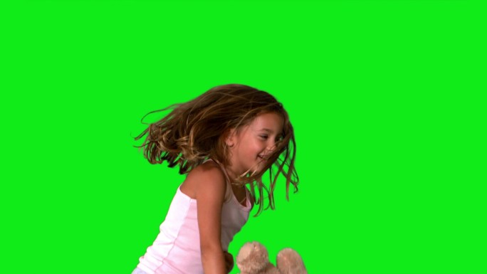 小女孩跳上跳下和旋转与泰迪熊在绿色屏幕慢动作