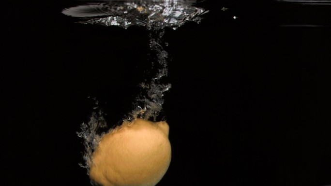柠檬在黑色背景下以超慢的动作落入水中