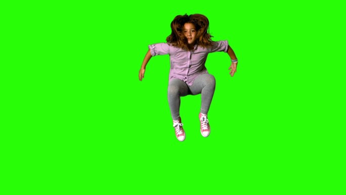 快乐的小女孩在慢动作的绿色屏幕上跳跃