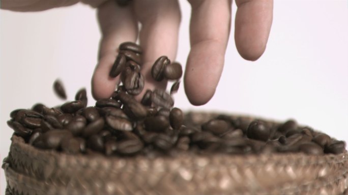 手抓咖啡豆在白色背景下慢镜头