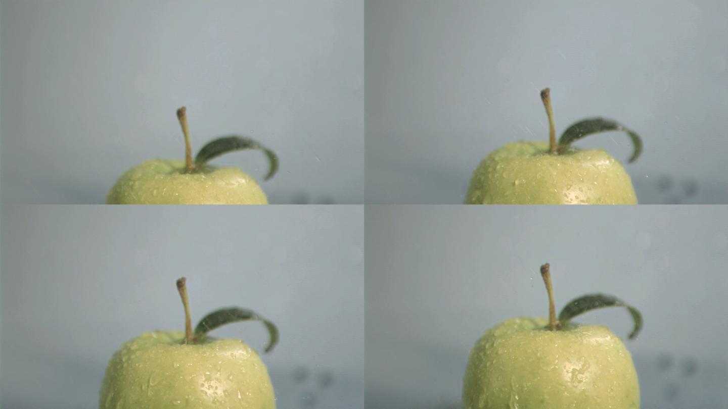 水滴落在青苹果上慢镜头，在灰色背景下