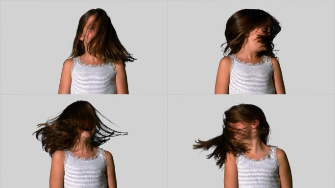 在慢镜头中，小女孩在白色背景上摇着头发