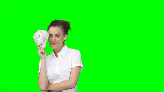 在绿色的背景下，一个女人把脸藏在一把钱扇后面