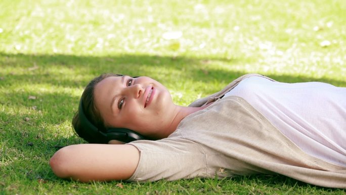 一位妇女正躺在草地上听音乐
