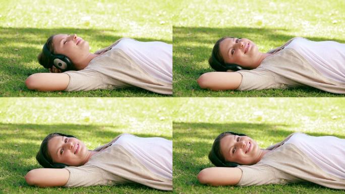 一位妇女正躺在草地上听音乐