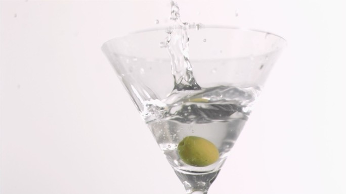 在白色背景下，橄榄在杜松子酒中以超慢的动作落下