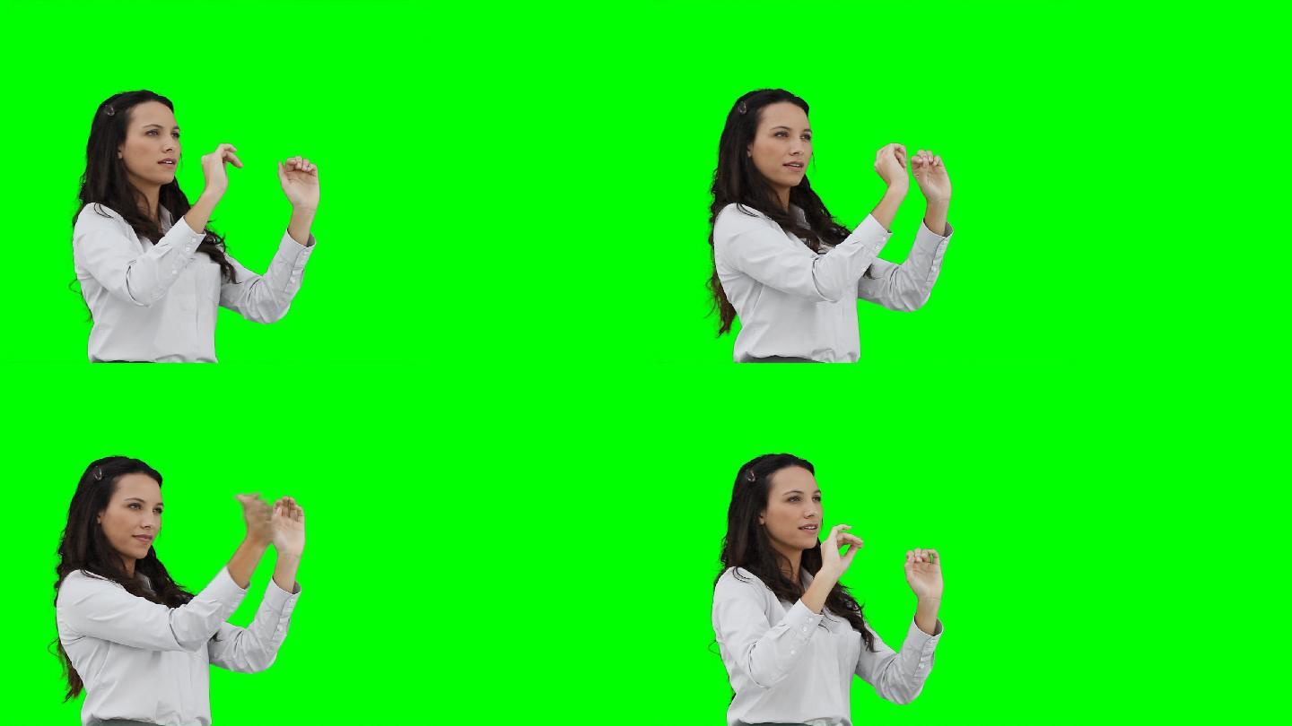 一个亚裔女性做虚拟手势在绿色背景下