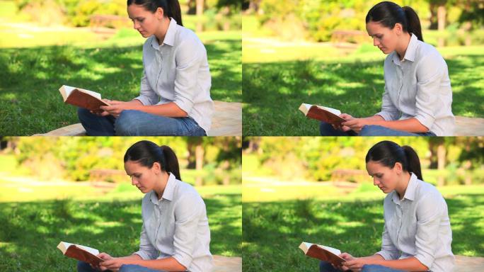 一个女人坐在公园的草地上看书