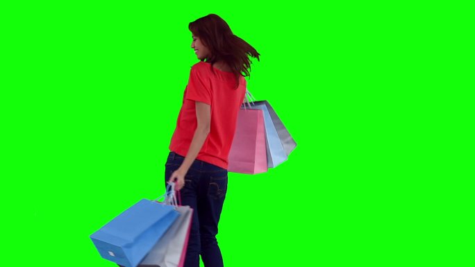 在绿色背景下晃动着购物袋的女人