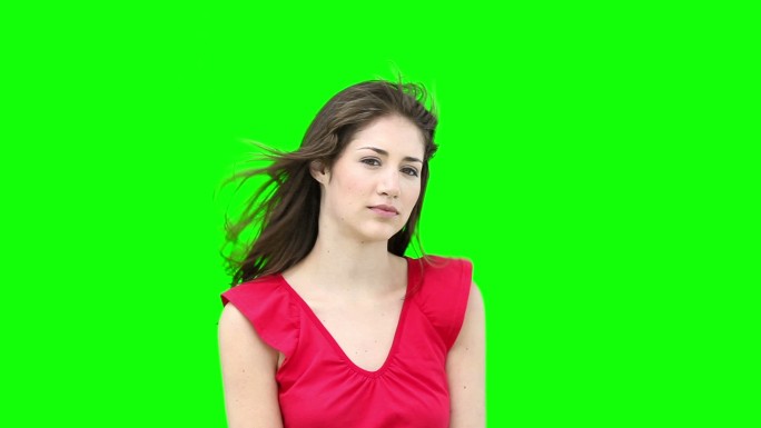 在绿色背景下整理头发的女人看着相机