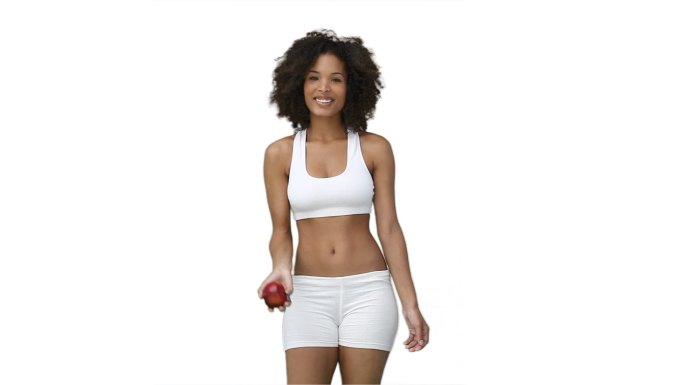 穿着训练服的女人在白色的背景下向上扔一个苹果
