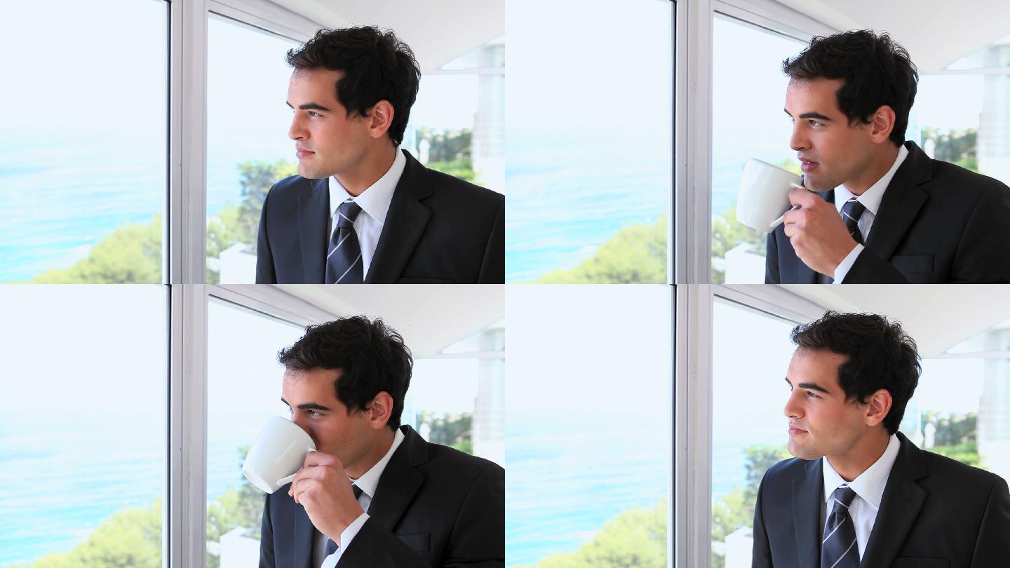 一个商人一边喝着咖啡，一边望着窗外