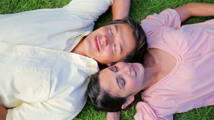 一对平静的夫妇躺在公园的草地上