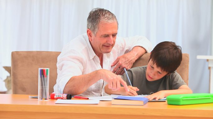 一个男人在客厅里哄他的孙子做作业