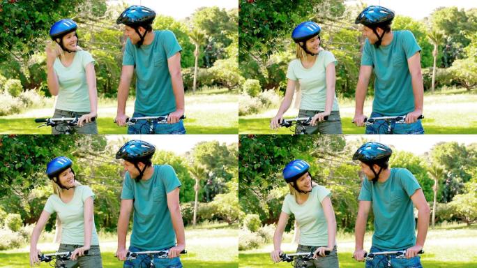 戴着自行车头盔的夫妇在公园里骑自行车