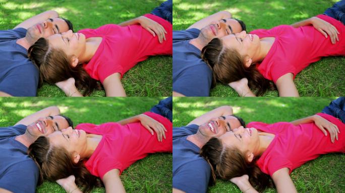一对平静的夫妇躺在草地上，在公园里打盹
