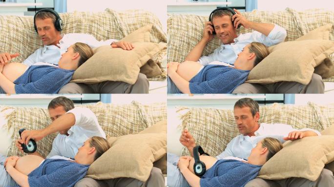 一个男人把耳机戴在他怀孕的妻子肚子上