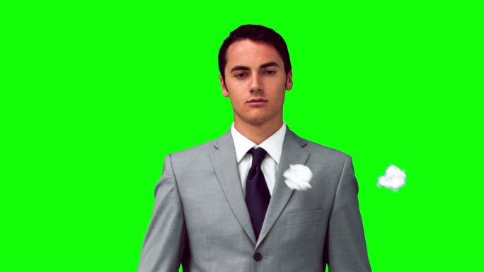 一个人在绿色背景下站在纸球下的慢镜头