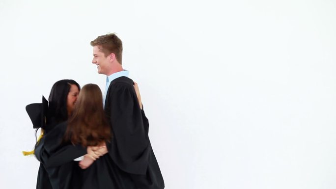 愉快的毕业生们在白色的背景下互相拥抱