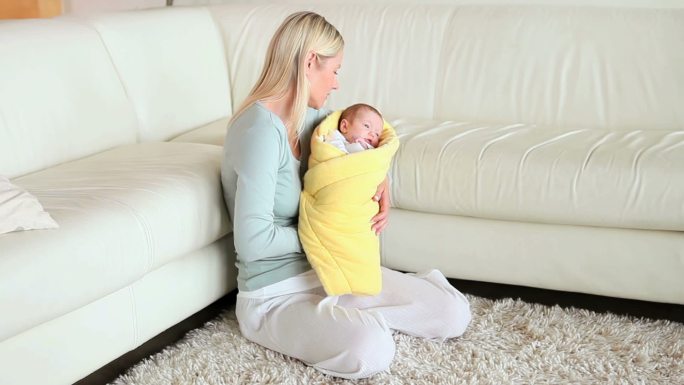 一个女人在客厅里亲吻和摇晃着怀里的婴儿