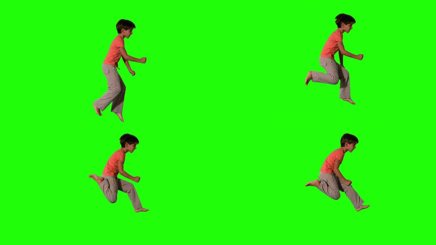 男孩跳跃在绿色屏幕的侧视图在慢动作