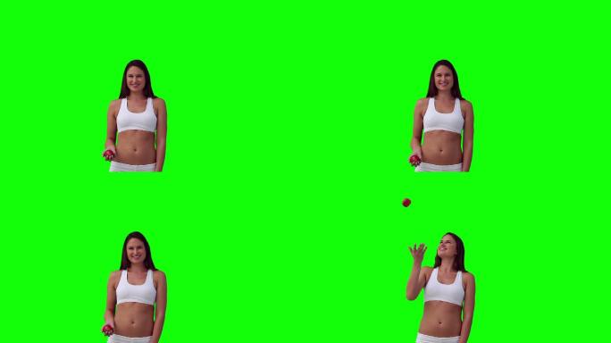 女子抛出一个球，然后在绿色背景下接住它