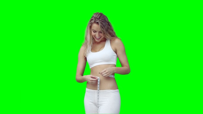 一个西方女性测量腰围，在绿色背景下