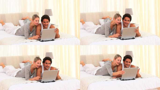 一对可爱的夫妇在床上用笔记本电脑