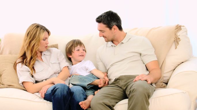 小男孩和他的父母在沙发上聊天