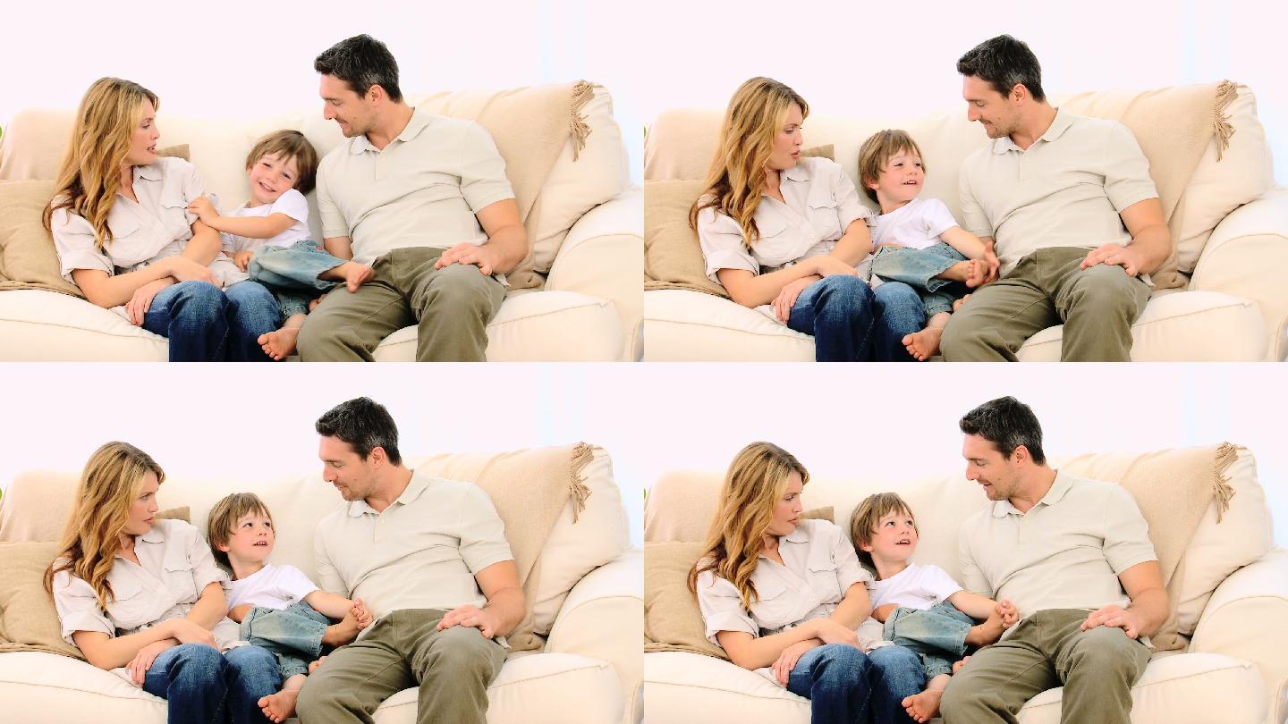 小男孩和他的父母在沙发上聊天