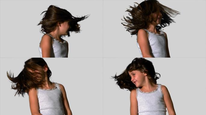 在慢镜头中，小女孩在白色背景上甩动她的头发