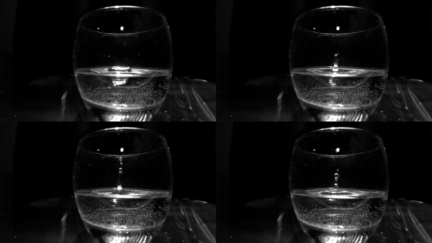 在黑色背景的慢镜头中，一滴水滴入玻璃杯