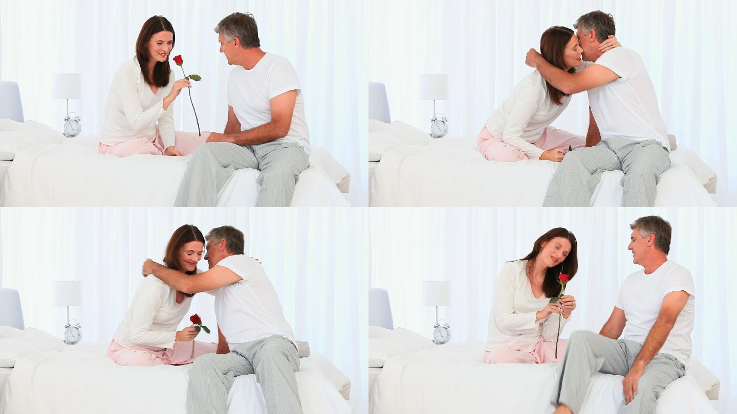 一个成熟的男人在卧室里向妻子献上一支玫瑰