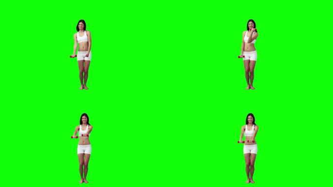 一个女人正在绿色的背景下用手练习重量