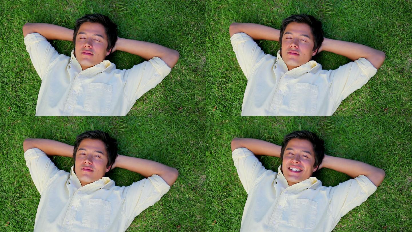 微笑的男人躺在他花园的草地上