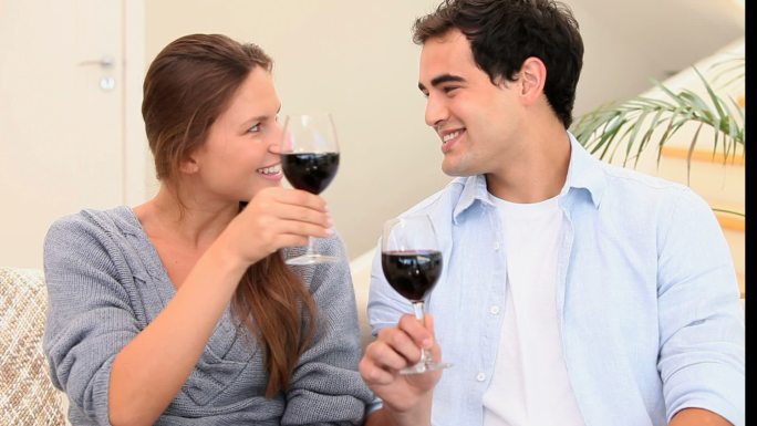 Couple toasting with glasses of wine in the living