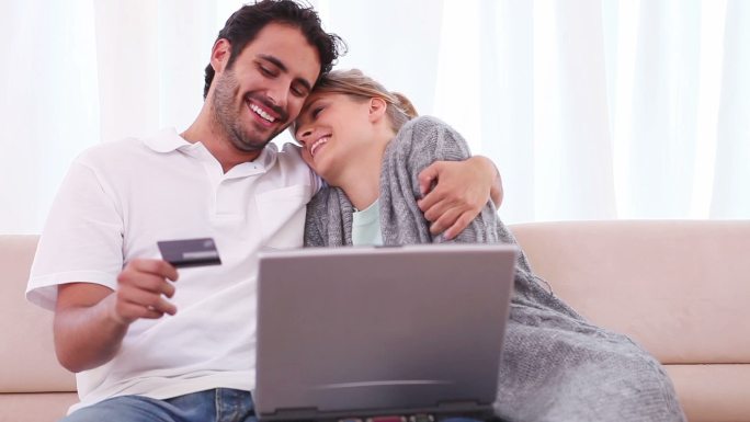一对夫妇坐在客厅里用笔记本电脑刷信用卡