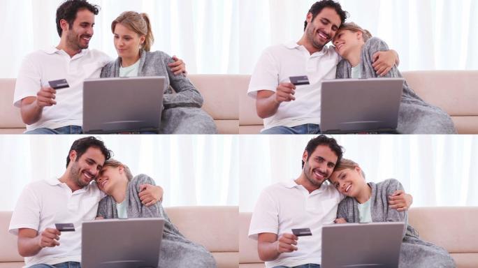 一对夫妇坐在客厅里用笔记本电脑刷信用卡