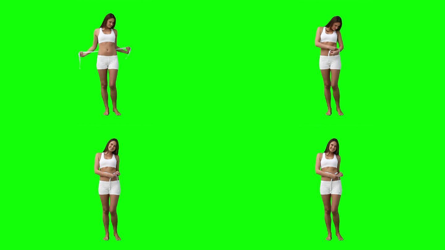 在绿色的背景下，一名妇女拿着卷尺绕在腰间
