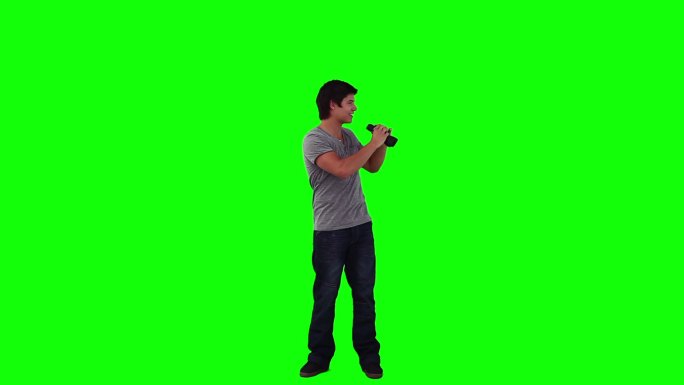 一个男人在绿色的背景下用双筒望远镜向四周看