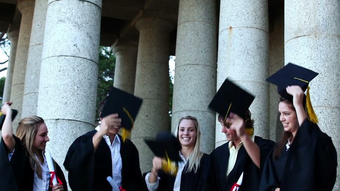 五个白人青年身着毕业礼服扔帽子实时拍摄