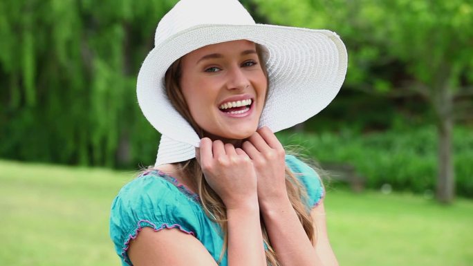 快乐的年轻女子举着她的帽沿在农村
