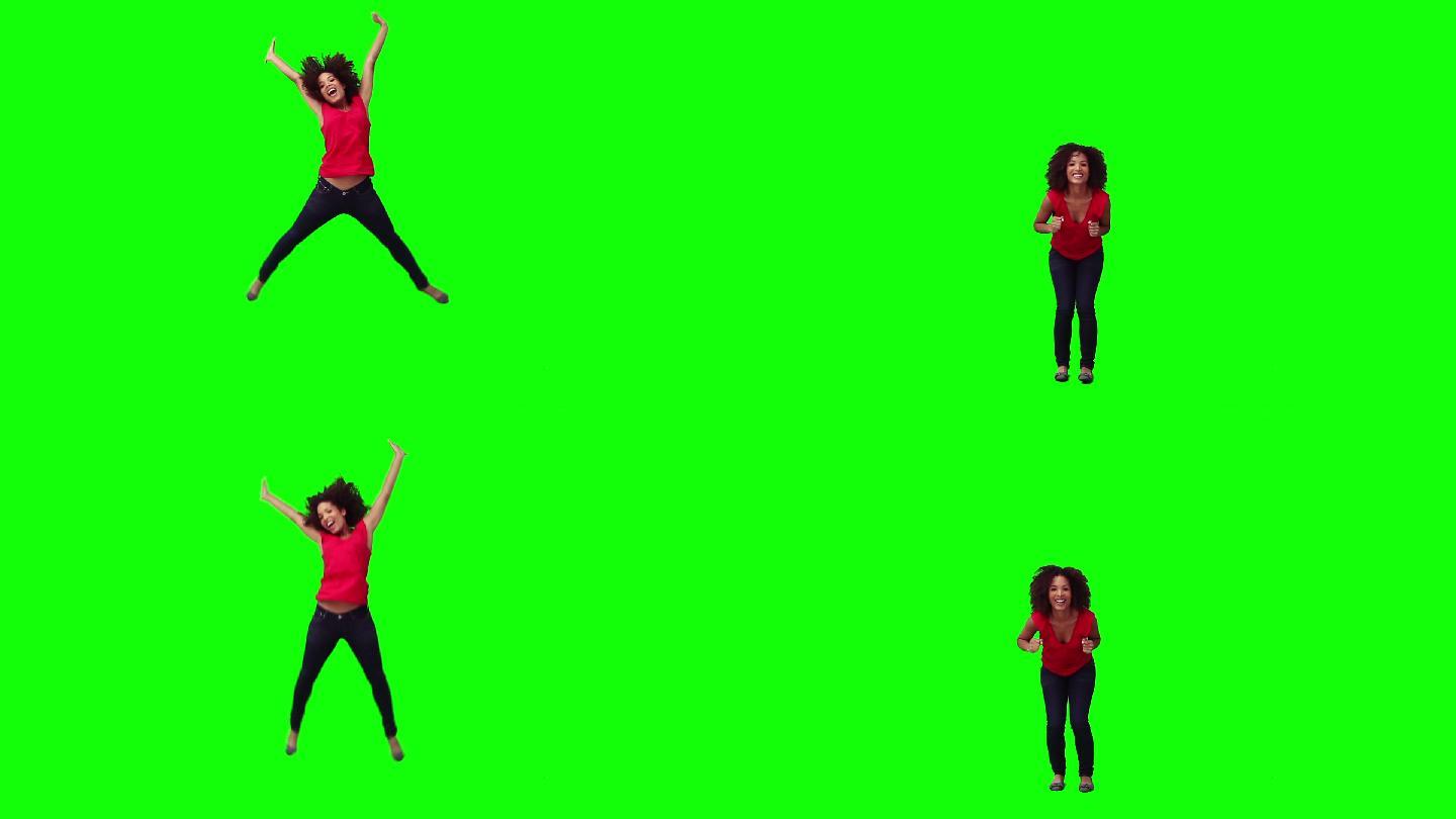 一个快乐的女人在绿色的背景前跳跃