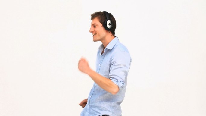 一个带着耳机在白色背景下听音乐的休闲男人