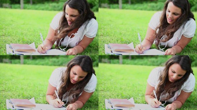一个黑发女人在公园的笔记本上写字