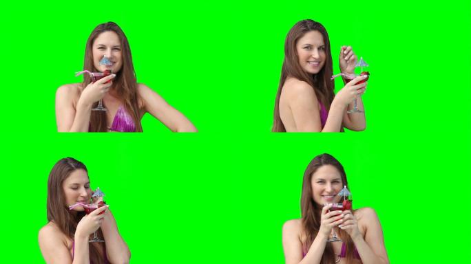 一个女人面带微笑，手里拿着饮料，背景是绿色的